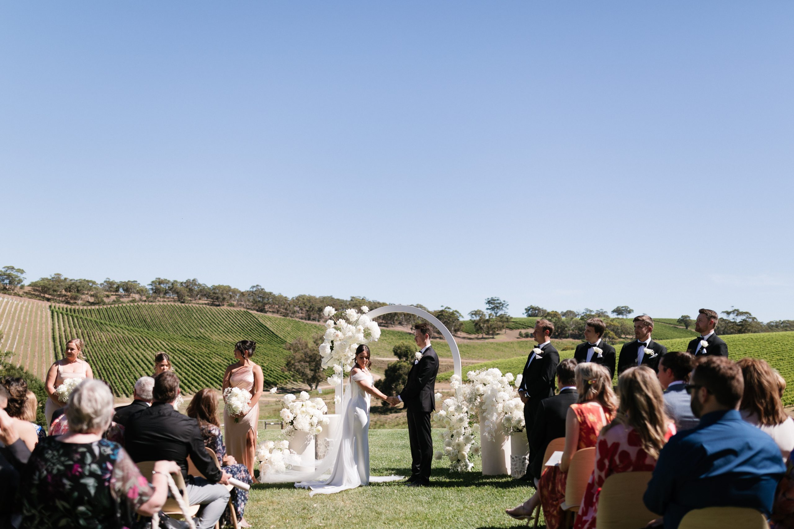 Couple in front of The modern approach white arch wedding arbor, Jack Small Photography