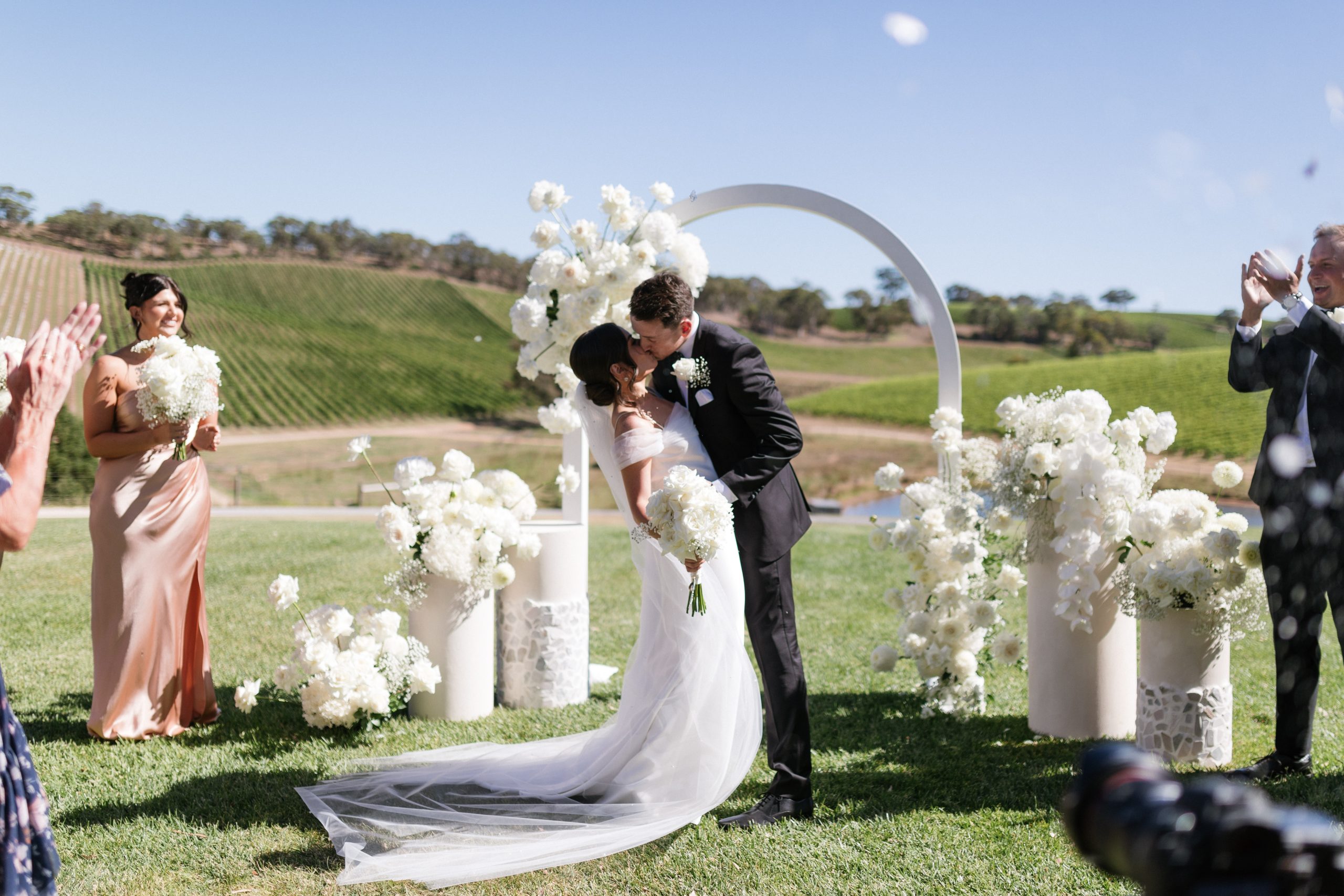 Couple kissing in front of The modern approach white arch wedding arbor, Jack Small Photography