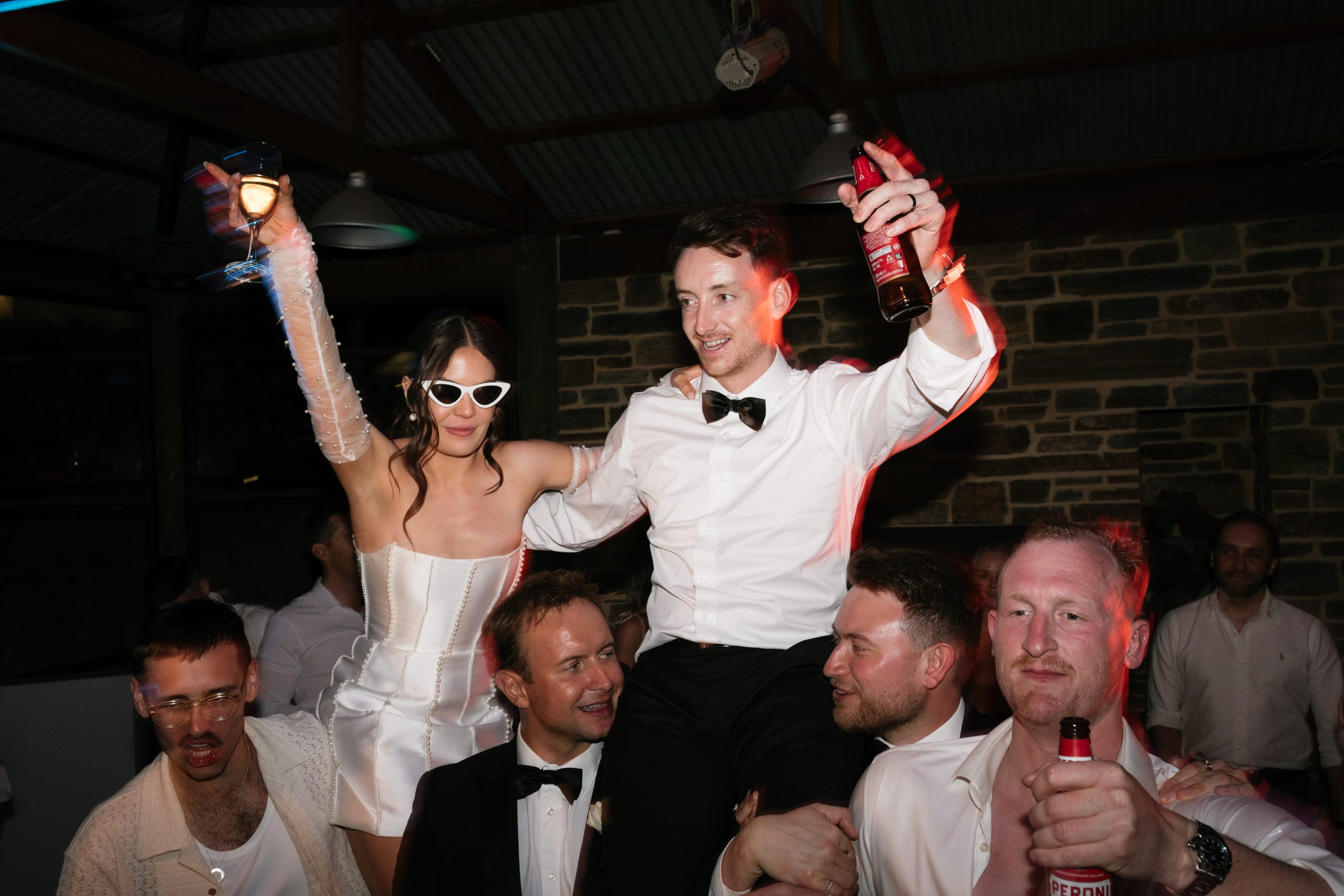 Bride and groom bing lifted in air at wedding reception. photographer Jack Small