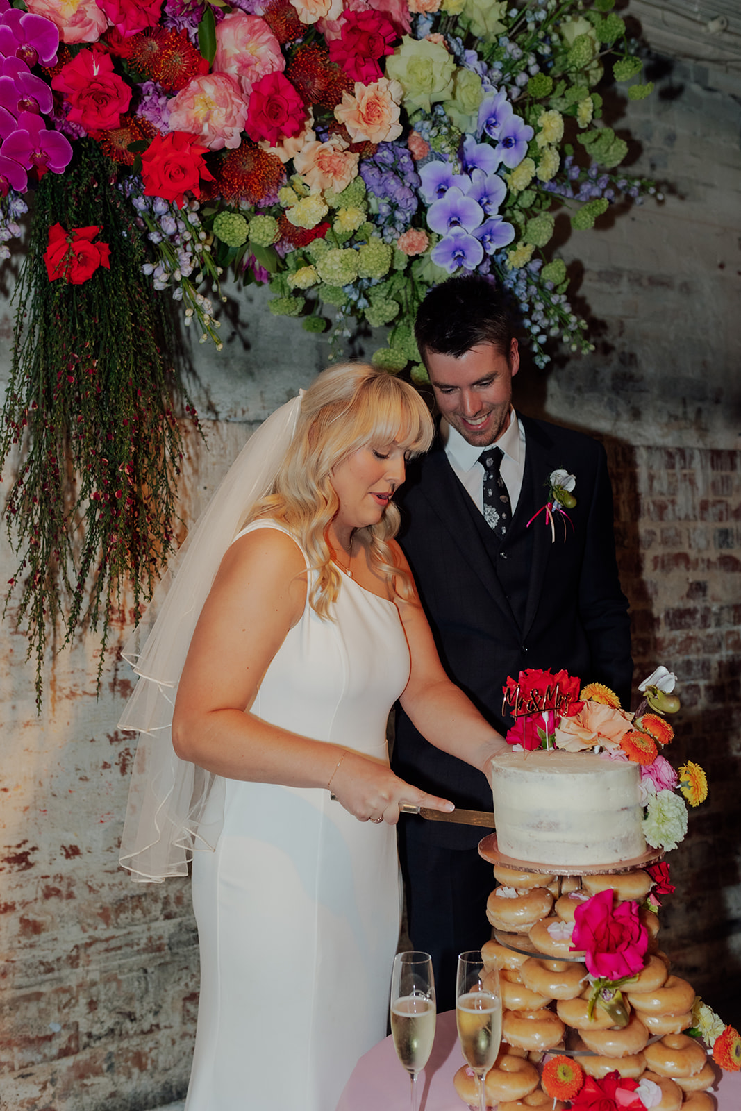 Bride and groom cutting cake at Intimate wedding infused with fun and colour in the cake and floral styling