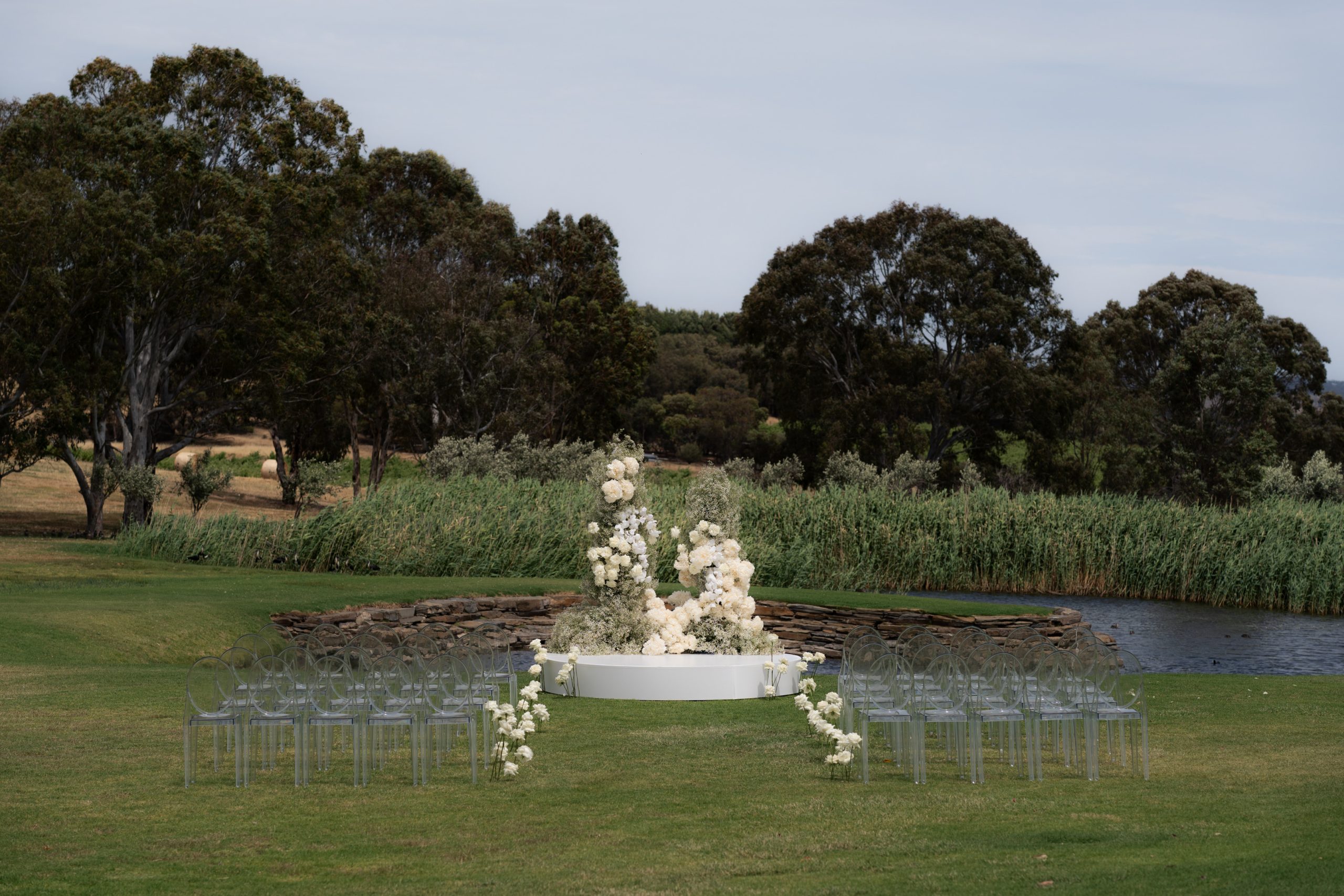 Wedding arbor elevated on white platform with clear chairs modern and timeless styling