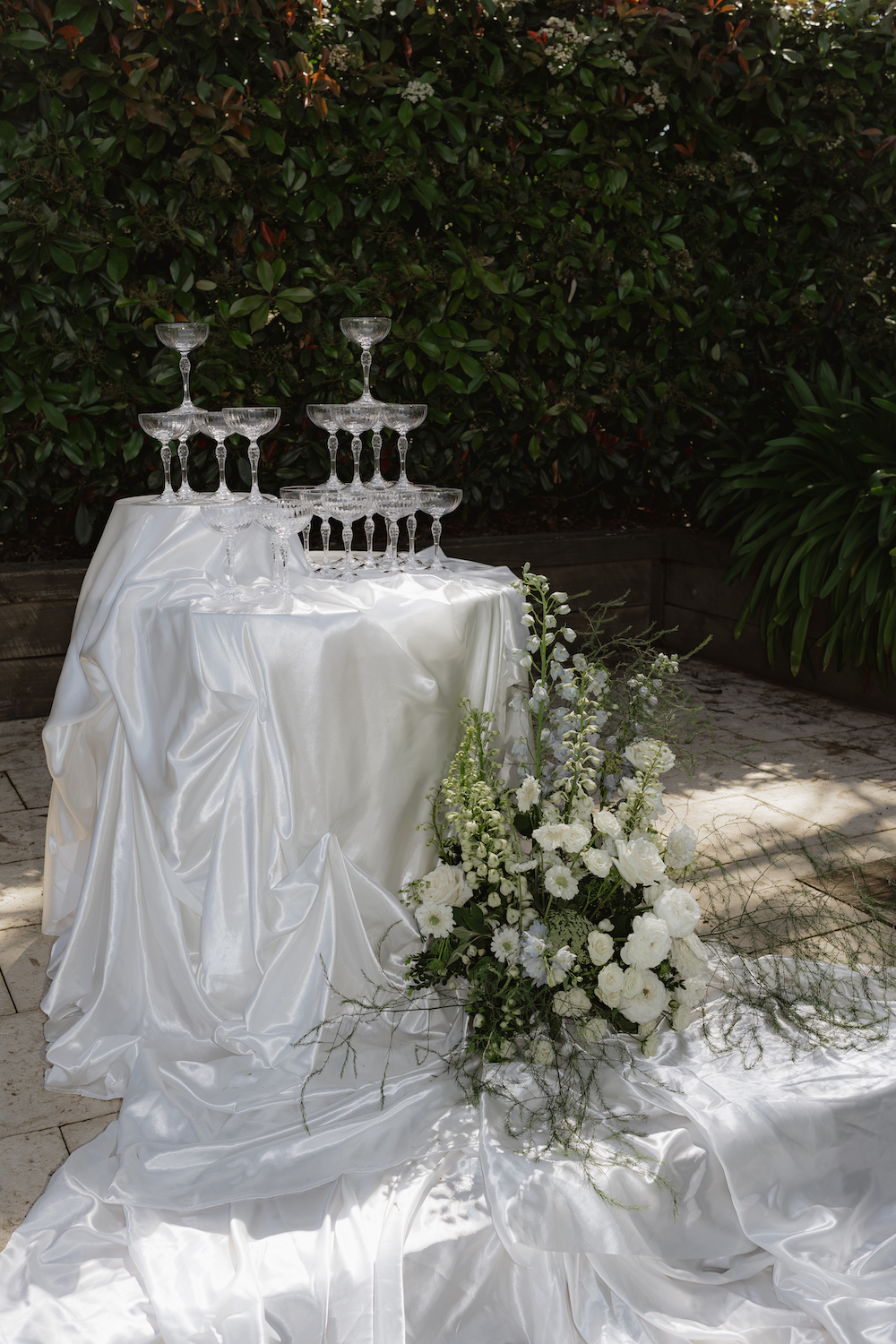 Champaign tower draped in white silky fabric with florals up the sidee