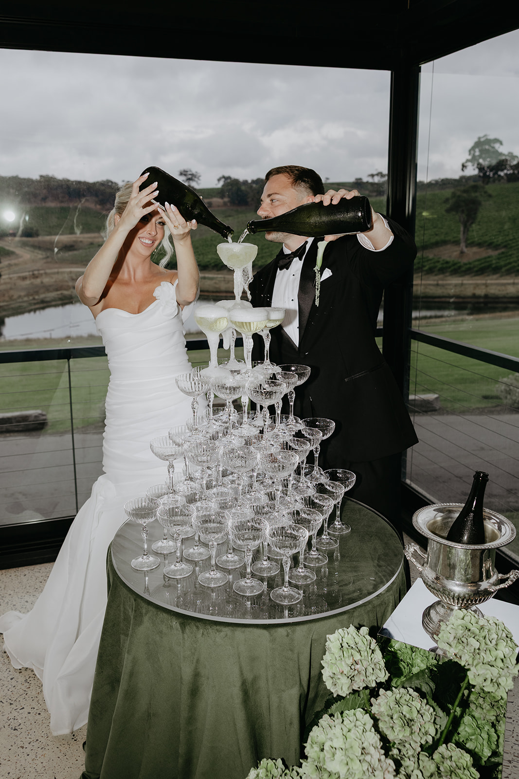 Bride and groom pouring champagne into champagne tower