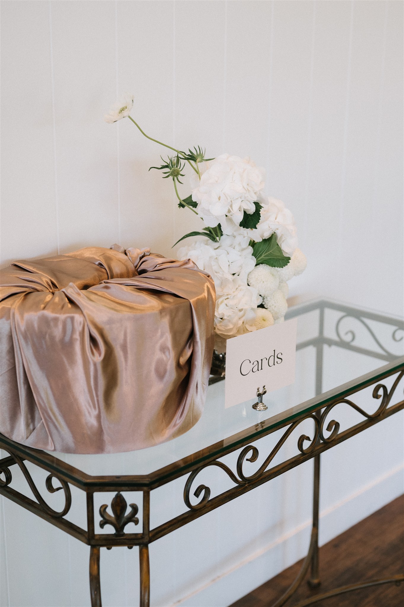 Glass wedding gift table at wedding reception with white flowers and a card box wrapped in silk