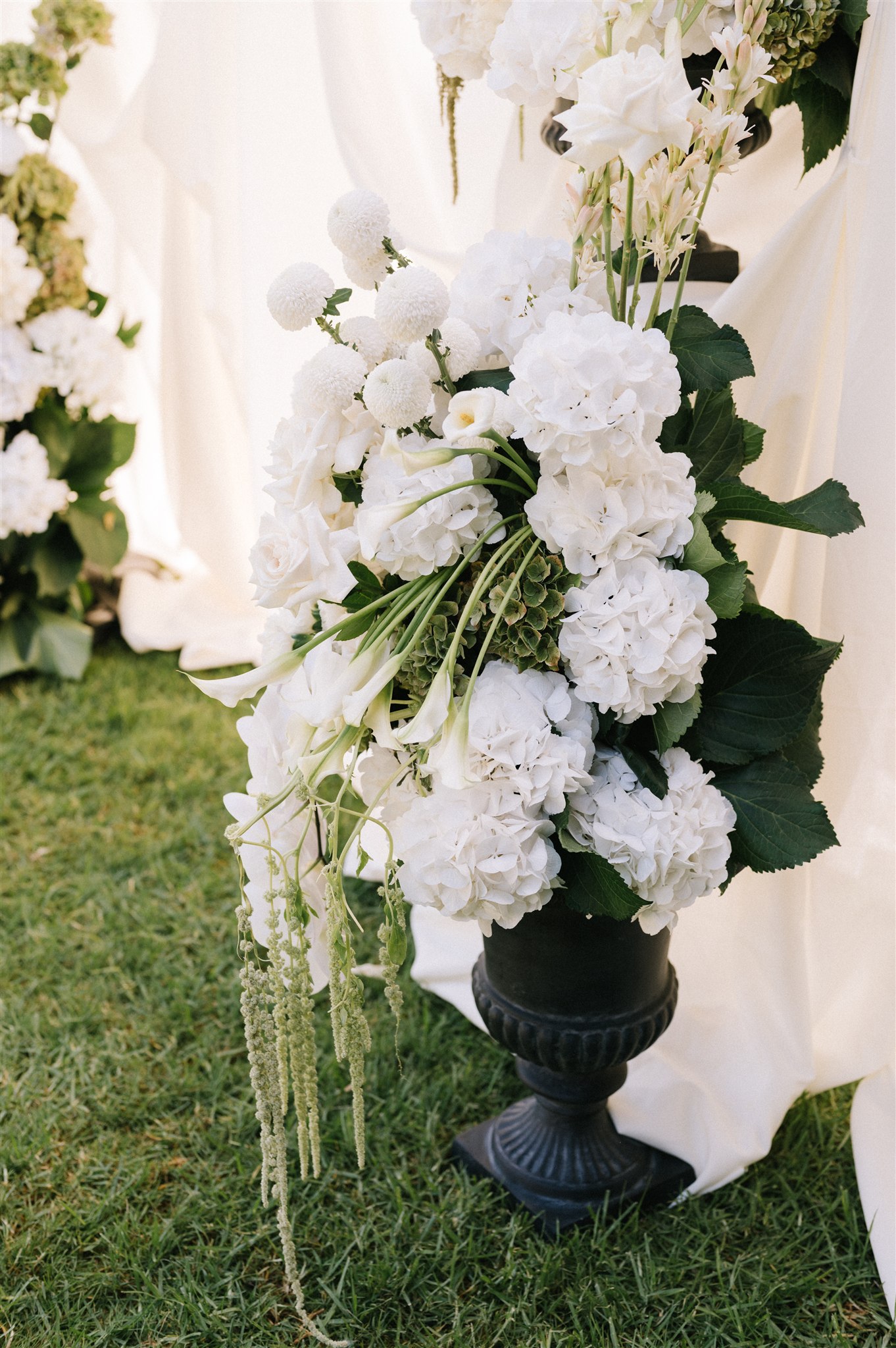 Ground floral arrangement for wedding arbor with layers of luxury fabric creating timeless and elegant styling