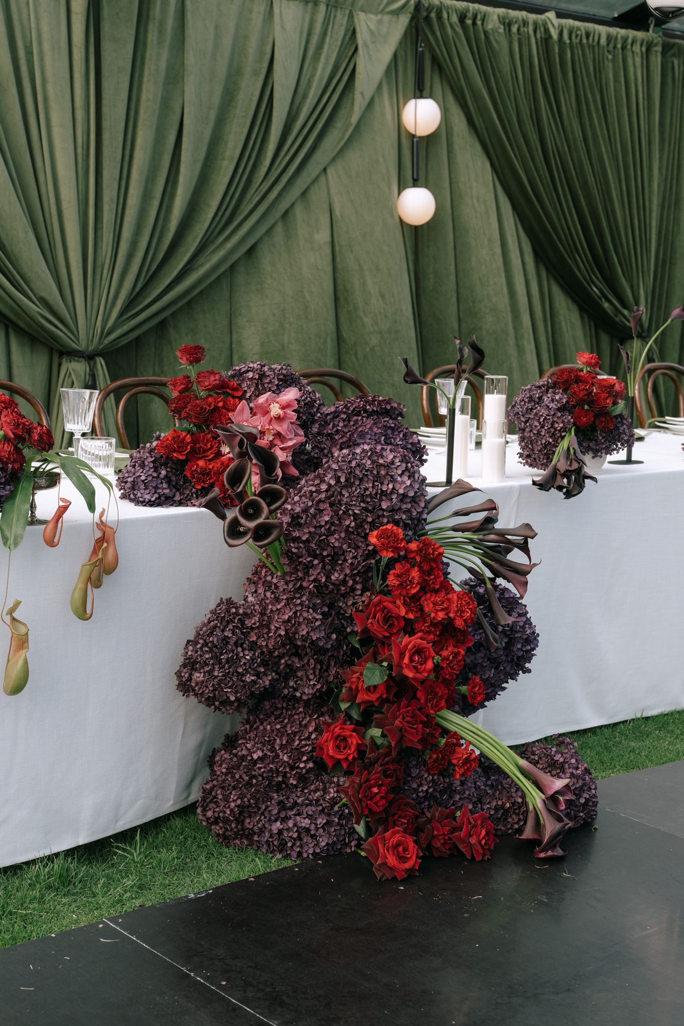 Floor floral display for bridal table with dark reds and purples
