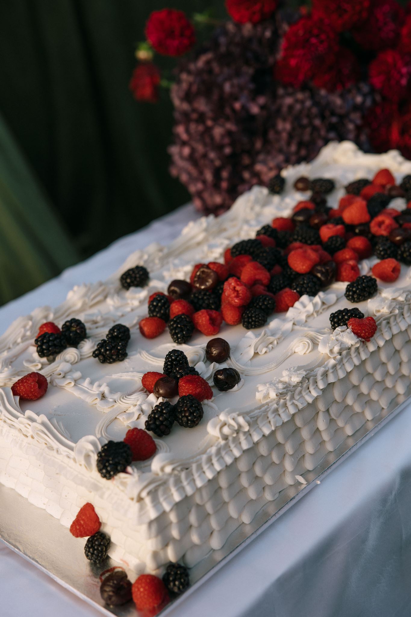 Off white wedding cake covered in raspberries and blackberries
