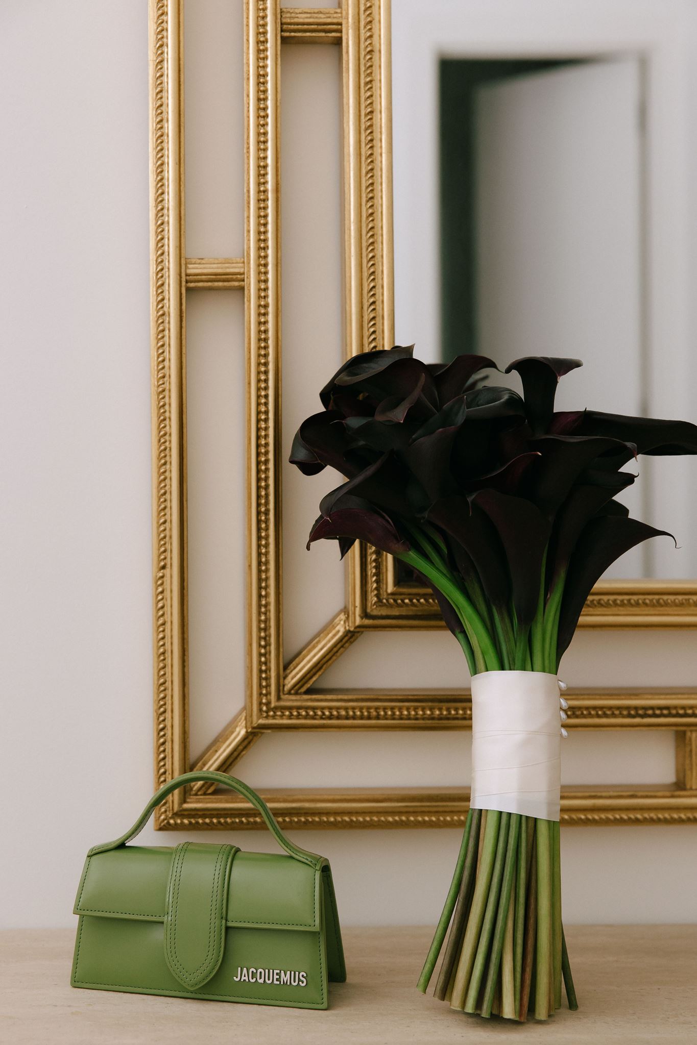 Dark iris wedding bouquet and green handbag displayed in front of gold mirror