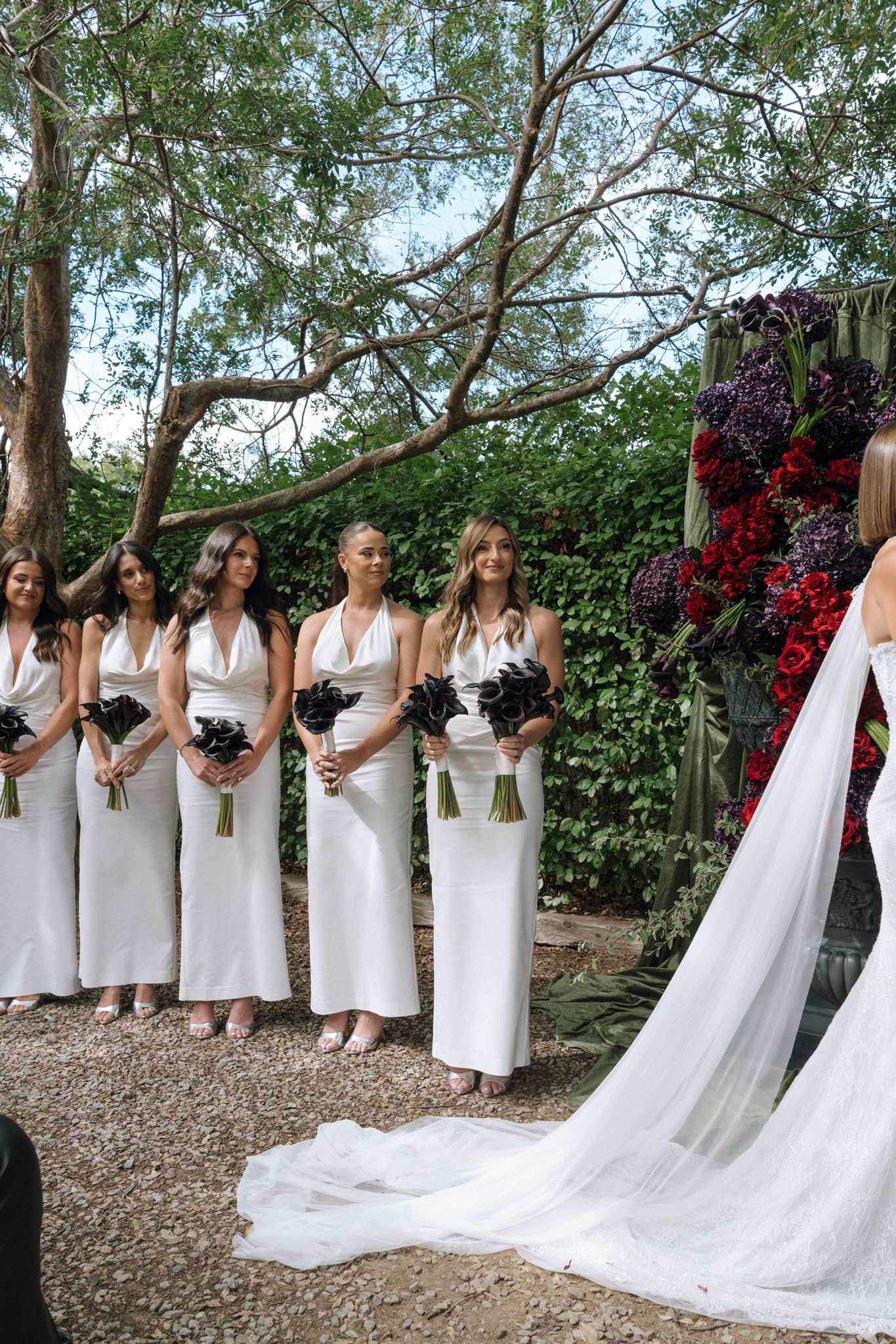 Bridesmaids dressed in matching white with dark purple floral bouquets