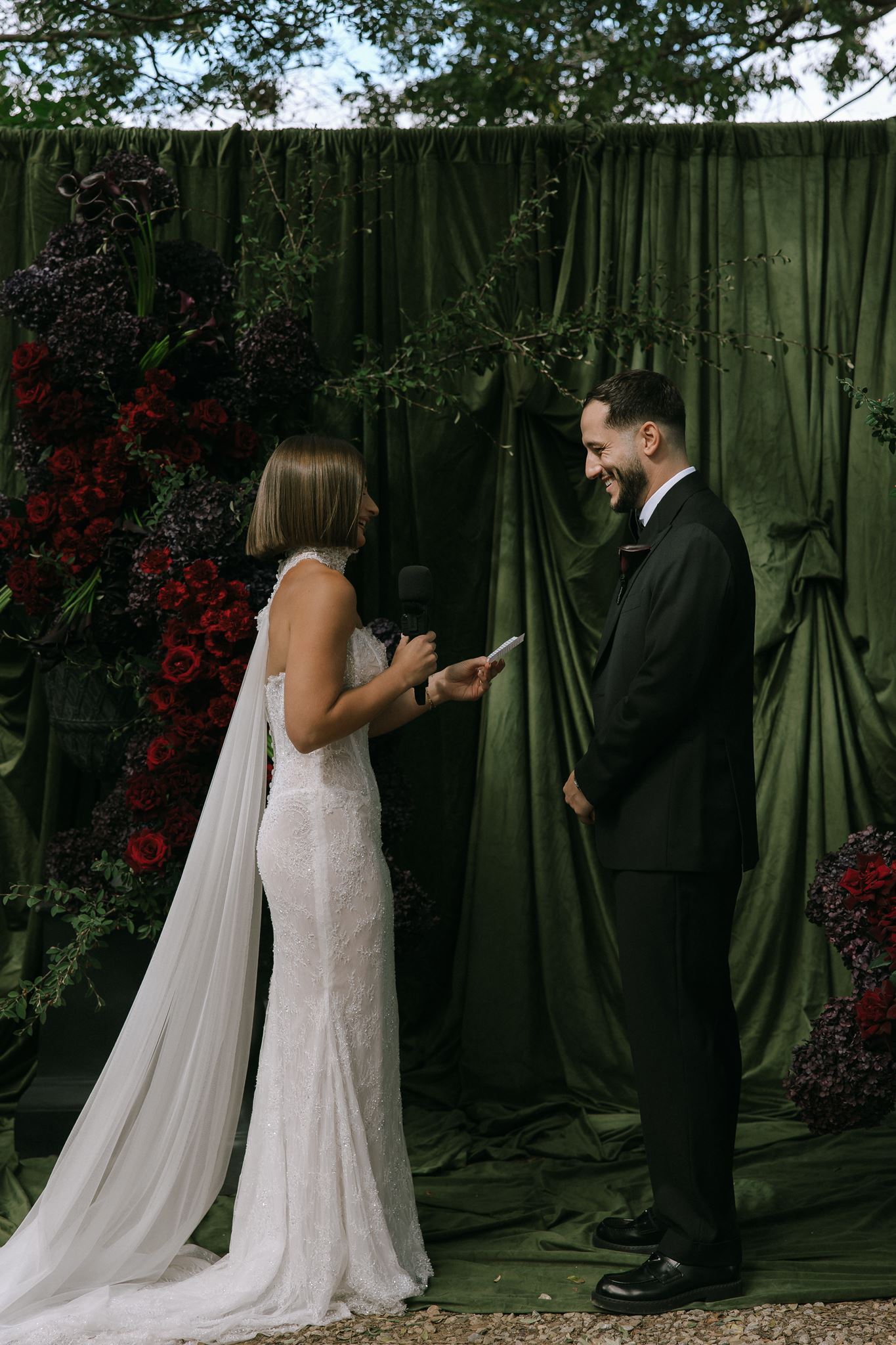 Rich green draped velvet wedding arbor with bride and groom reading nuptials