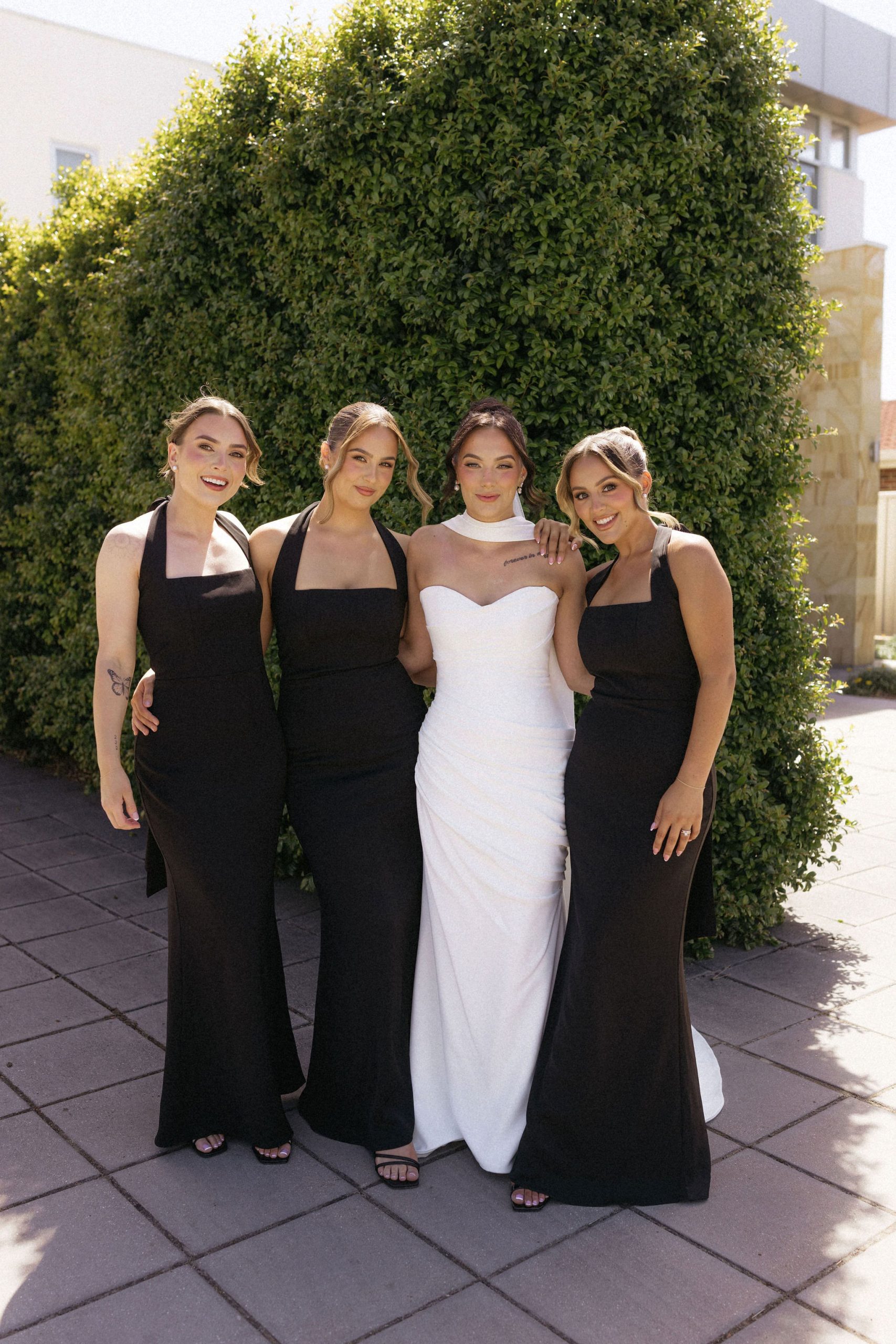 Bridal party wearing classic black dresses with bride in white love heart neckline dress