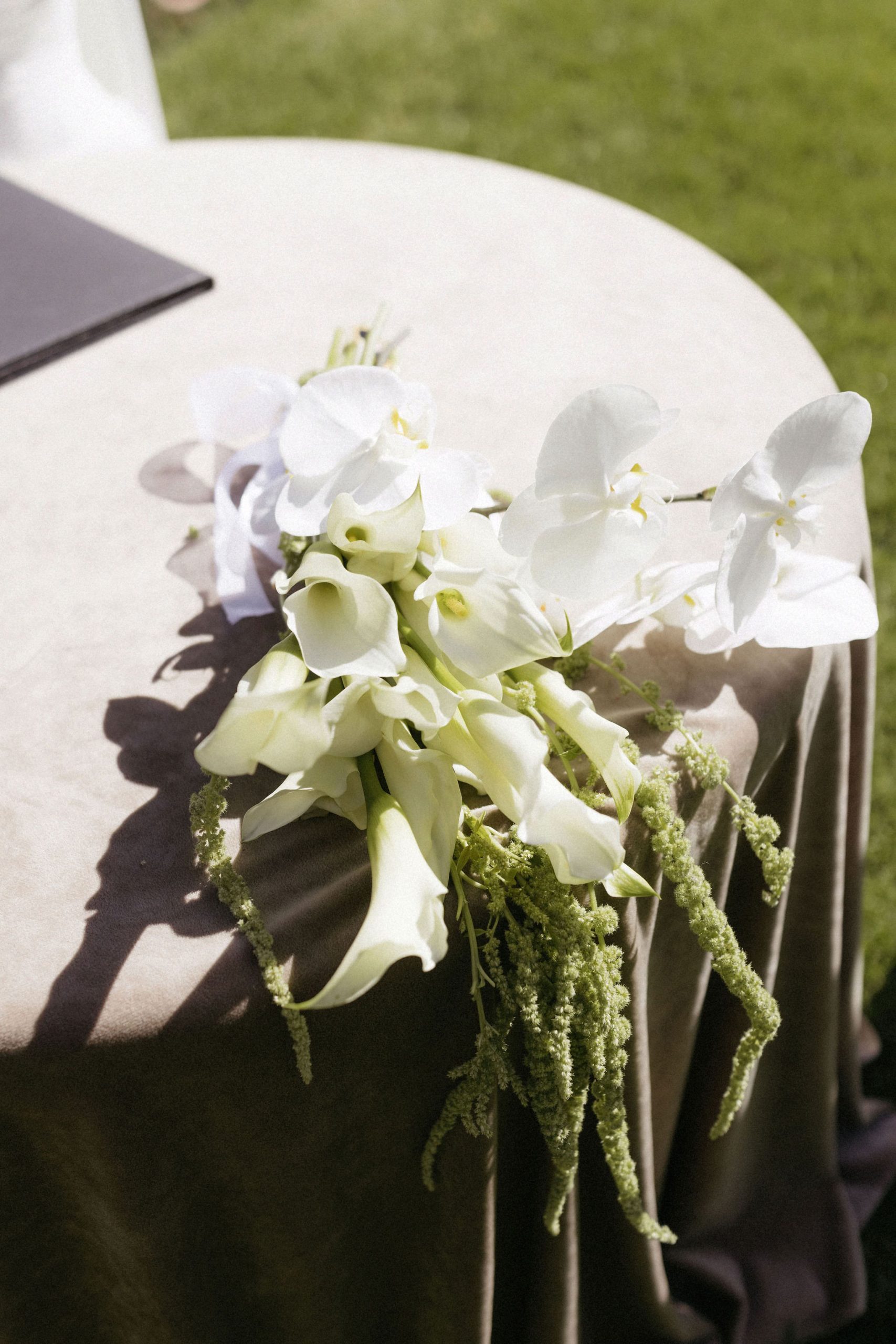 White and green bridal bouquet featuring orchards laid on wedding signing table