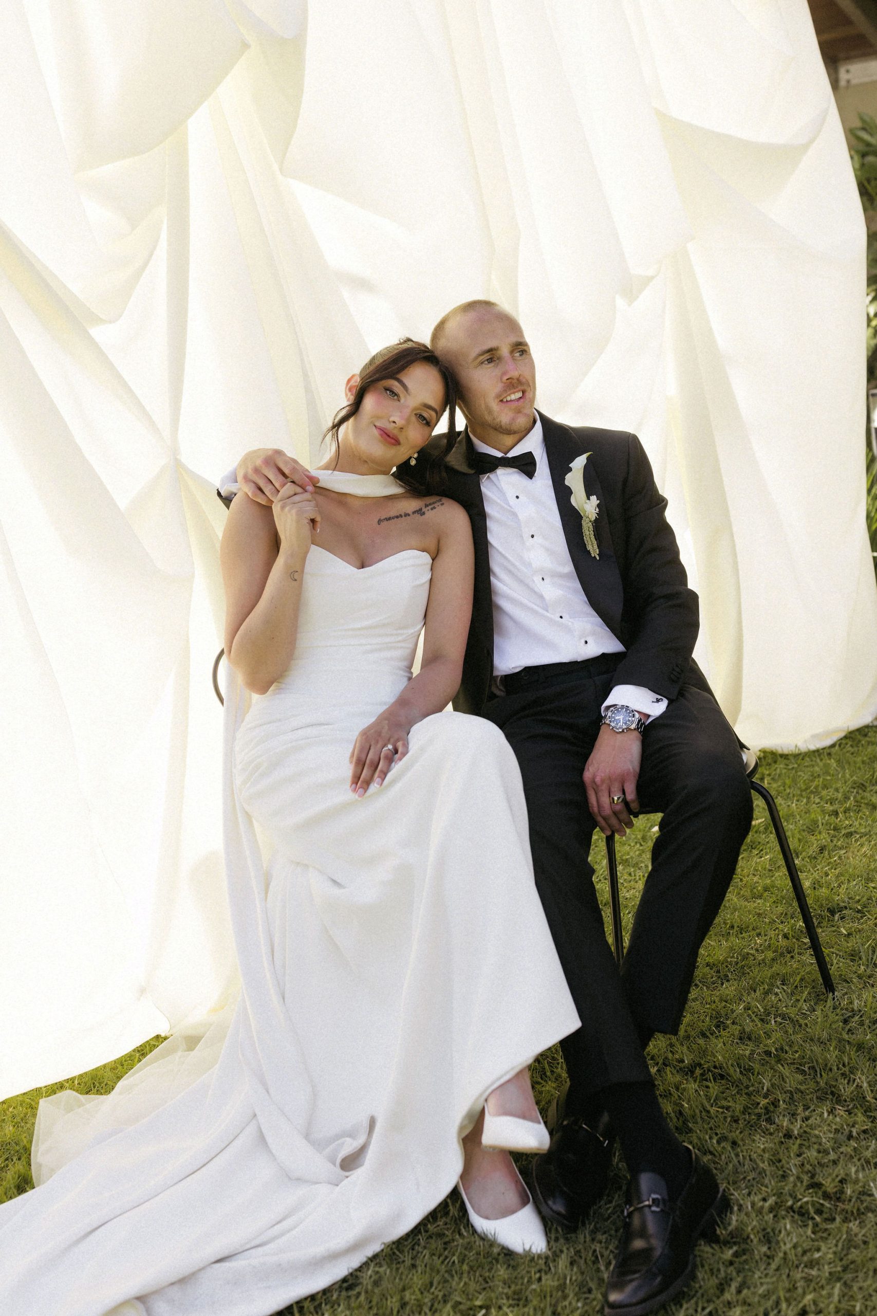 Bride and groom portrait sitting in front of layered hanging fabric