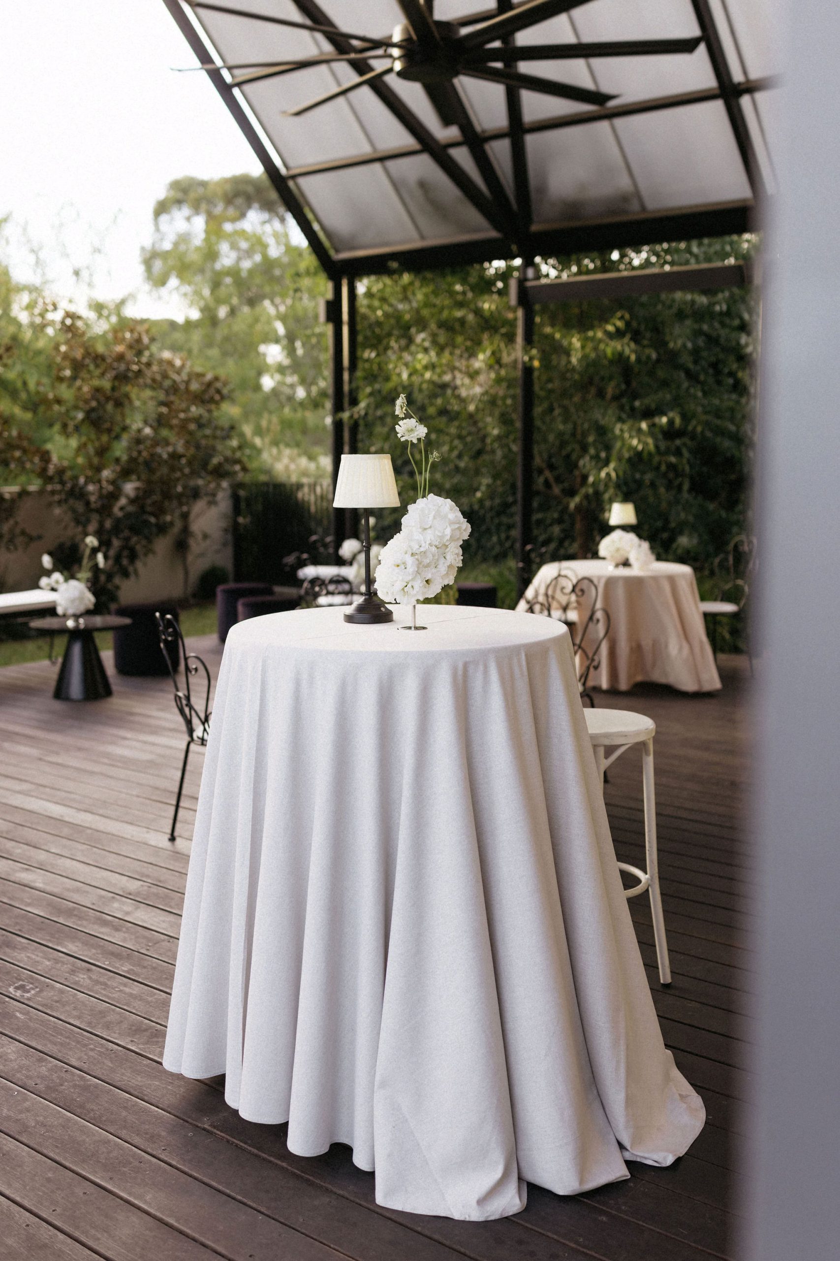 Small white floral arrangement and lamp on round wedding reception table at House on Haines