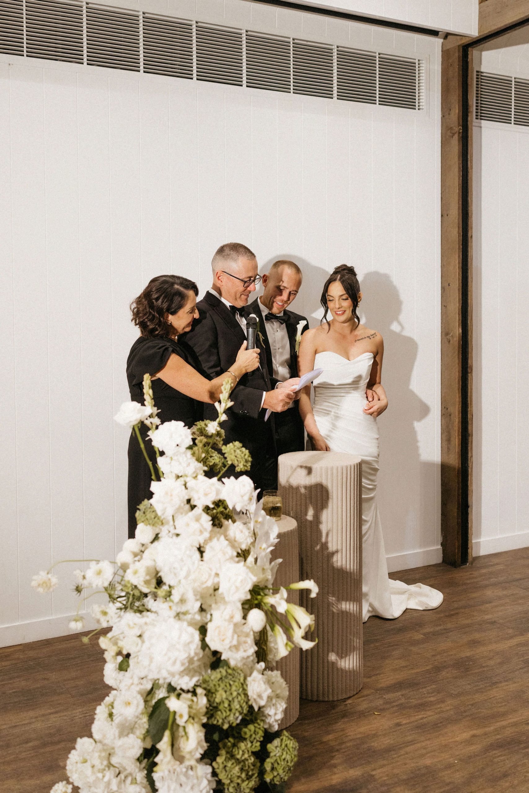 Family speech in front of stone pillar and white floral floor bouquet